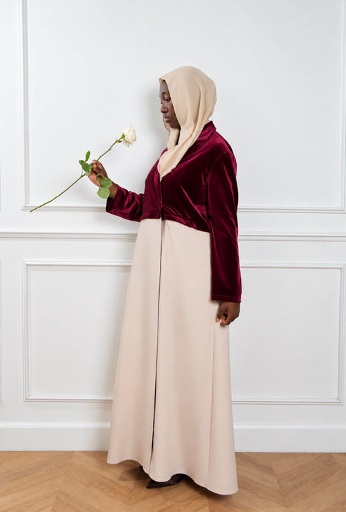 Abaya Opéra bordeaux et beige, portée de trois quarts avec une rose.